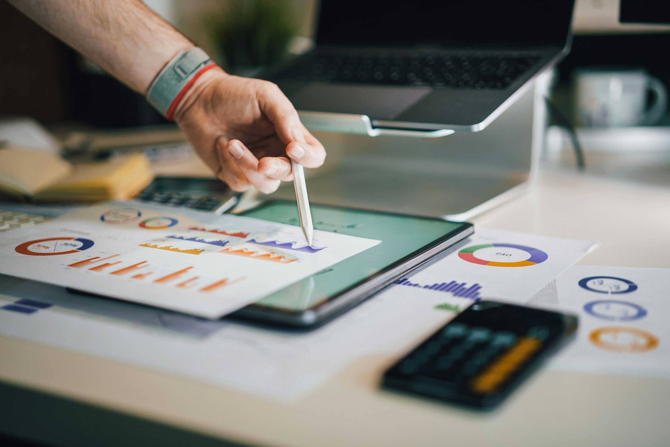 Hand analyzing IT downtime costs on tablet with financial graphs and charts