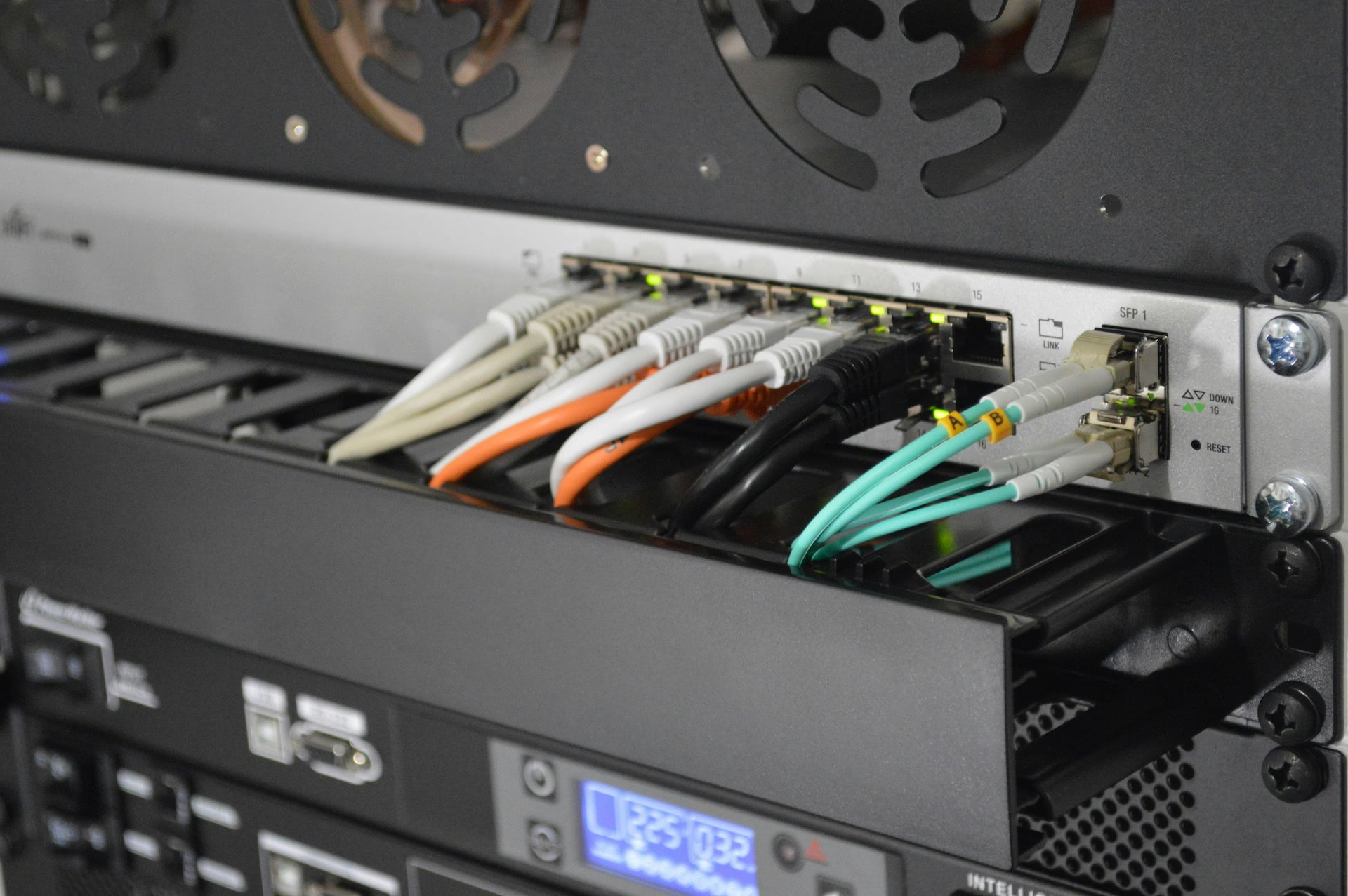 Close-up of a UniFi network switch with multiple Ethernet cables in a server rack, illustrating expert installation by Illini Tech Services