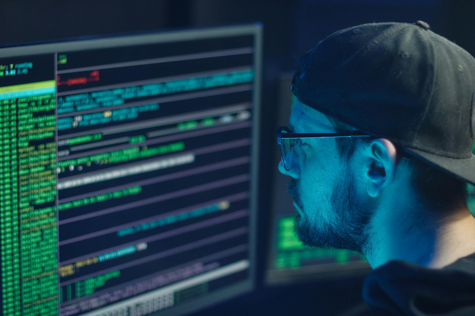 IT professional reviewing code on multiple computer monitors, representing Illini Tech Services’ advanced IT and security solutions