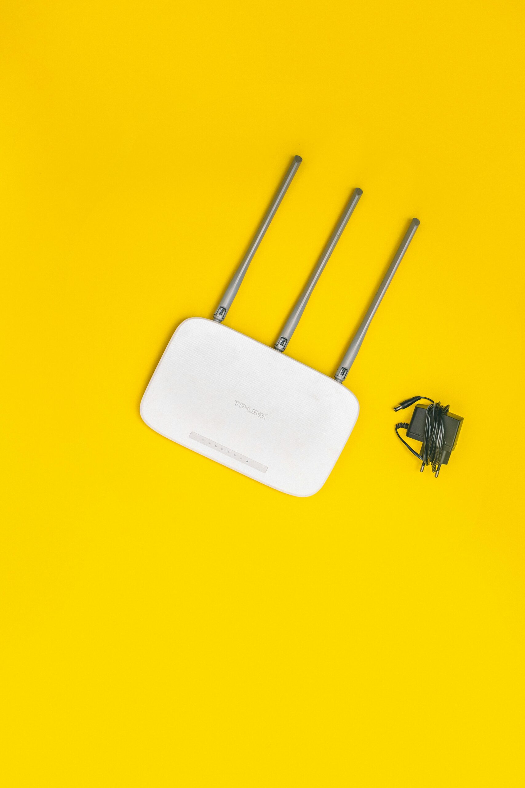 Wireless router with antennas and power cable on a yellow background symbolizing Wi-Fi performance optimization for businesses